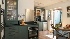 Une cuisine moderne dotée d’un four encastré, d’un lave-vaisselle et d’un coin repas avec une table et des chaises.