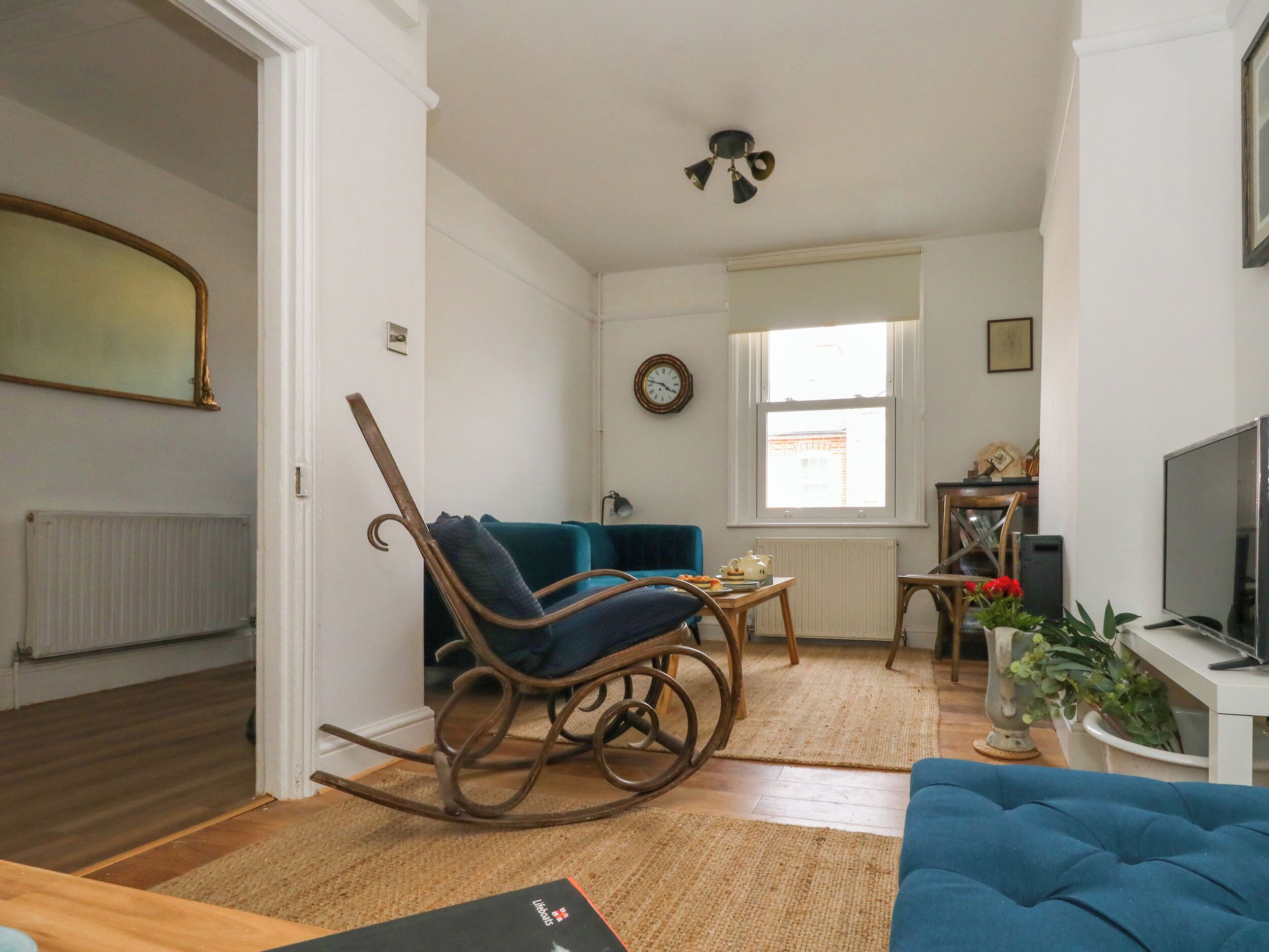A living room with a blue sofa, a rocking chair, a wooden coffee table, and a television.