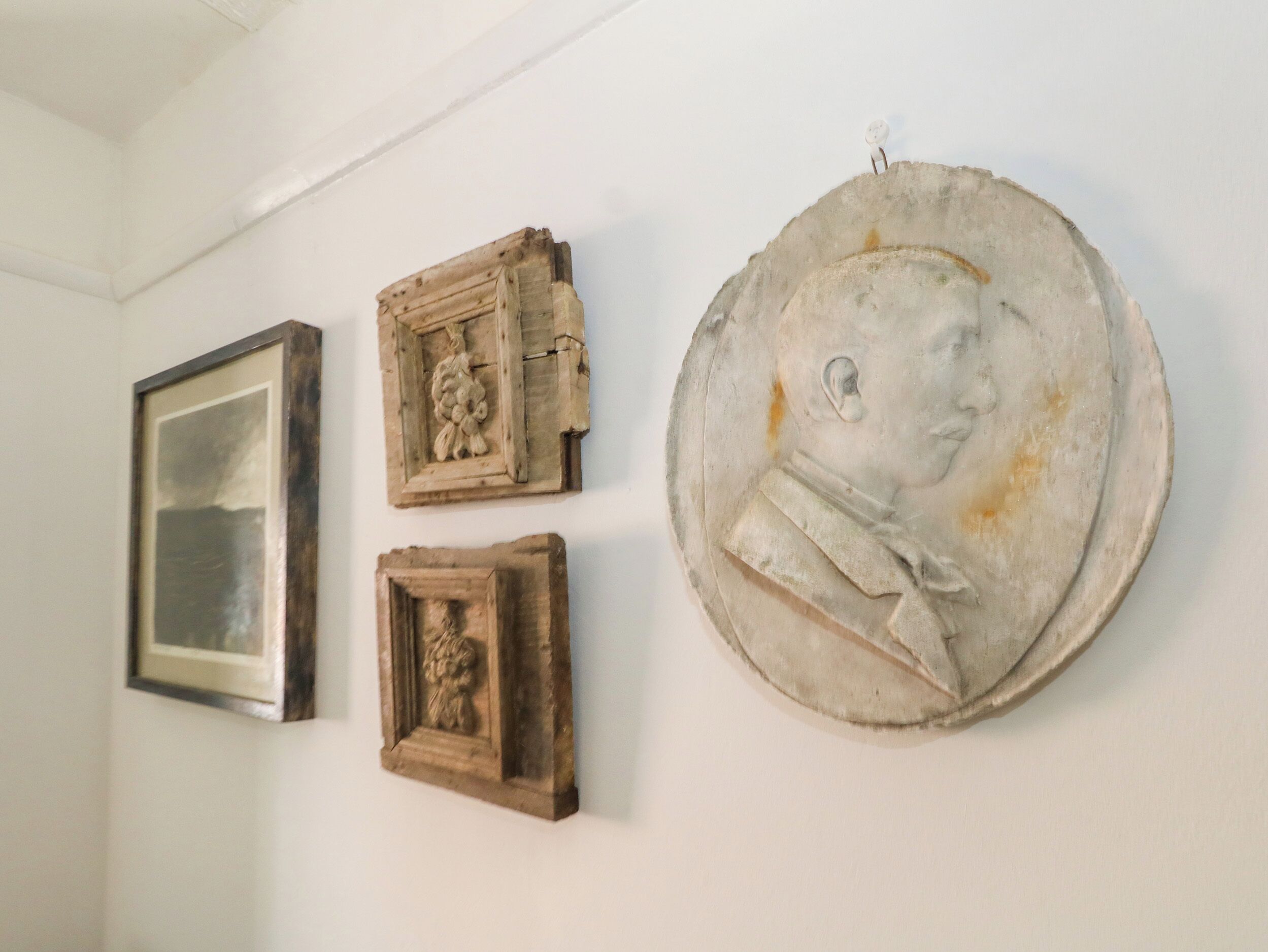 A wall with three framed artworks and a large circular sculpture.