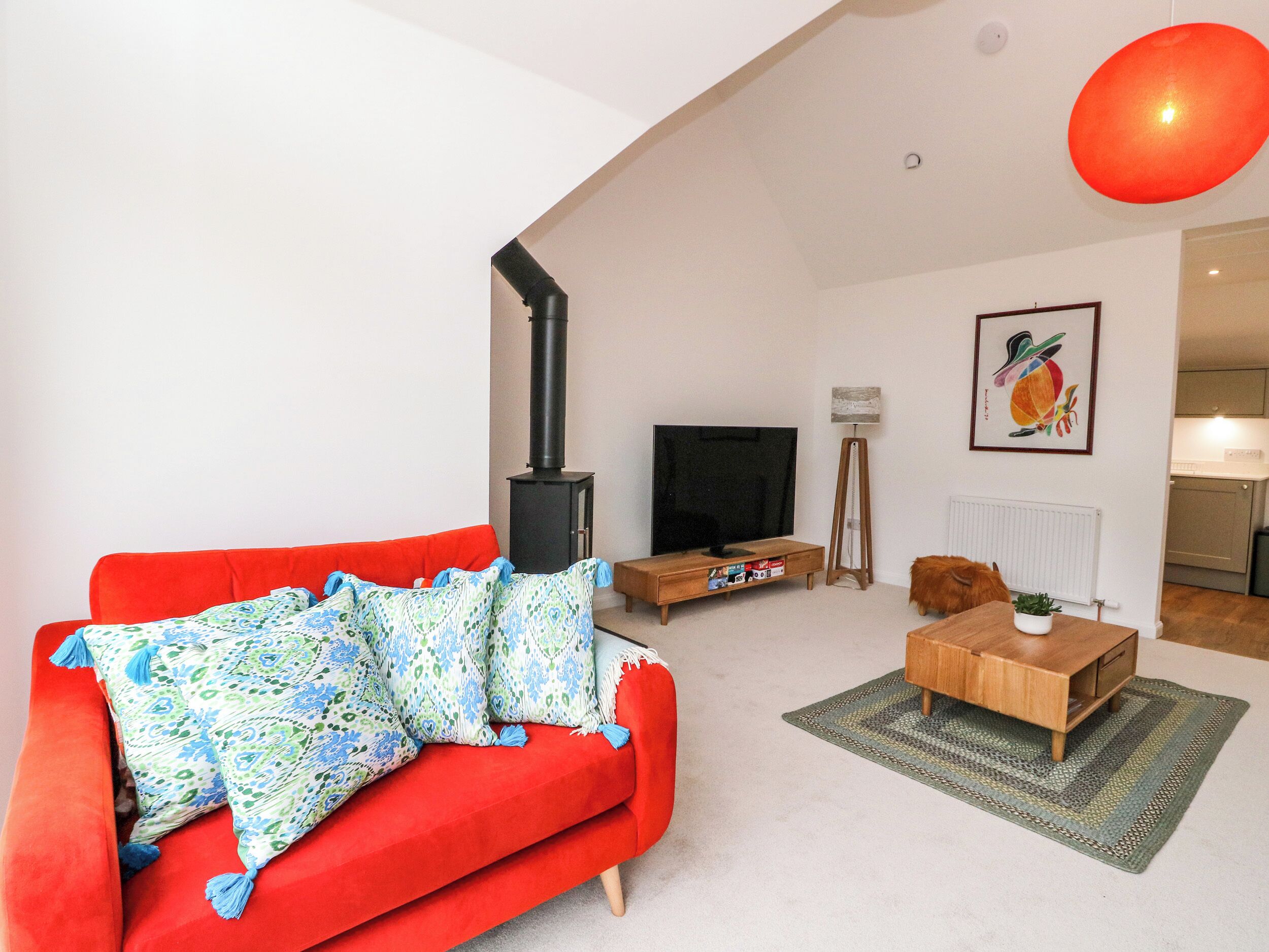 Una sala de estar con un sofá rojo, una chimenea negra, un televisor y un comedor con una mesa de madera.