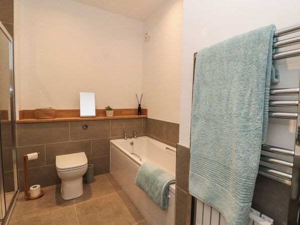 A modern bathroom with a toilet, bathtub, and towel rack. - Kalipé (Aberfeldy)