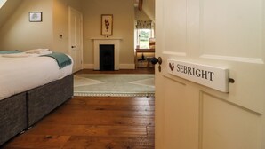 A cozy bedroom with a bed, a fireplace, and a door labeled "SEBRIGHT". - Hammonds Farmhouse (Stroud)