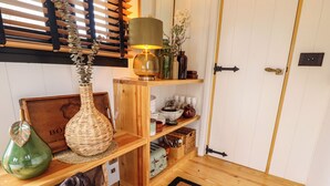 A wooden shelf with various items including a lamp, a vase, and decorative objects. - Herdwick Luxury Glamping (Retford)