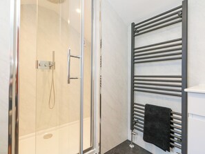 Une salle de bain moderne avec une douche à parois de verre, un porte-serviettes noir et des toilettes blanches.
