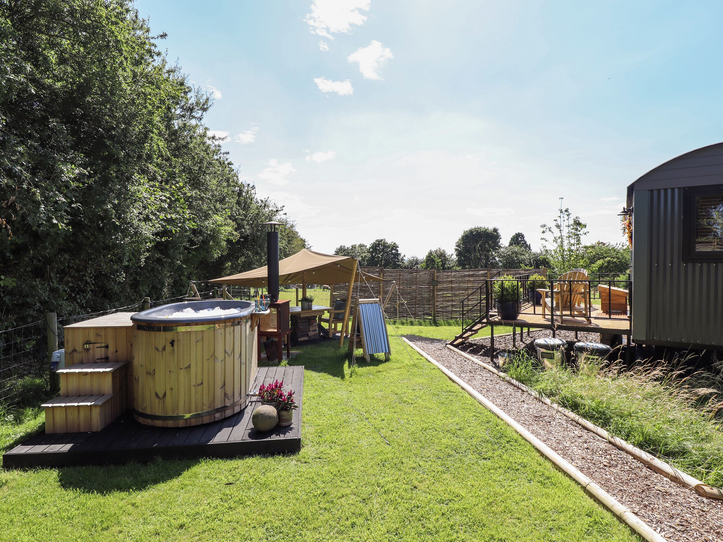 A hot tub, wooden deck, outdoor seating area, and a fenced garden.