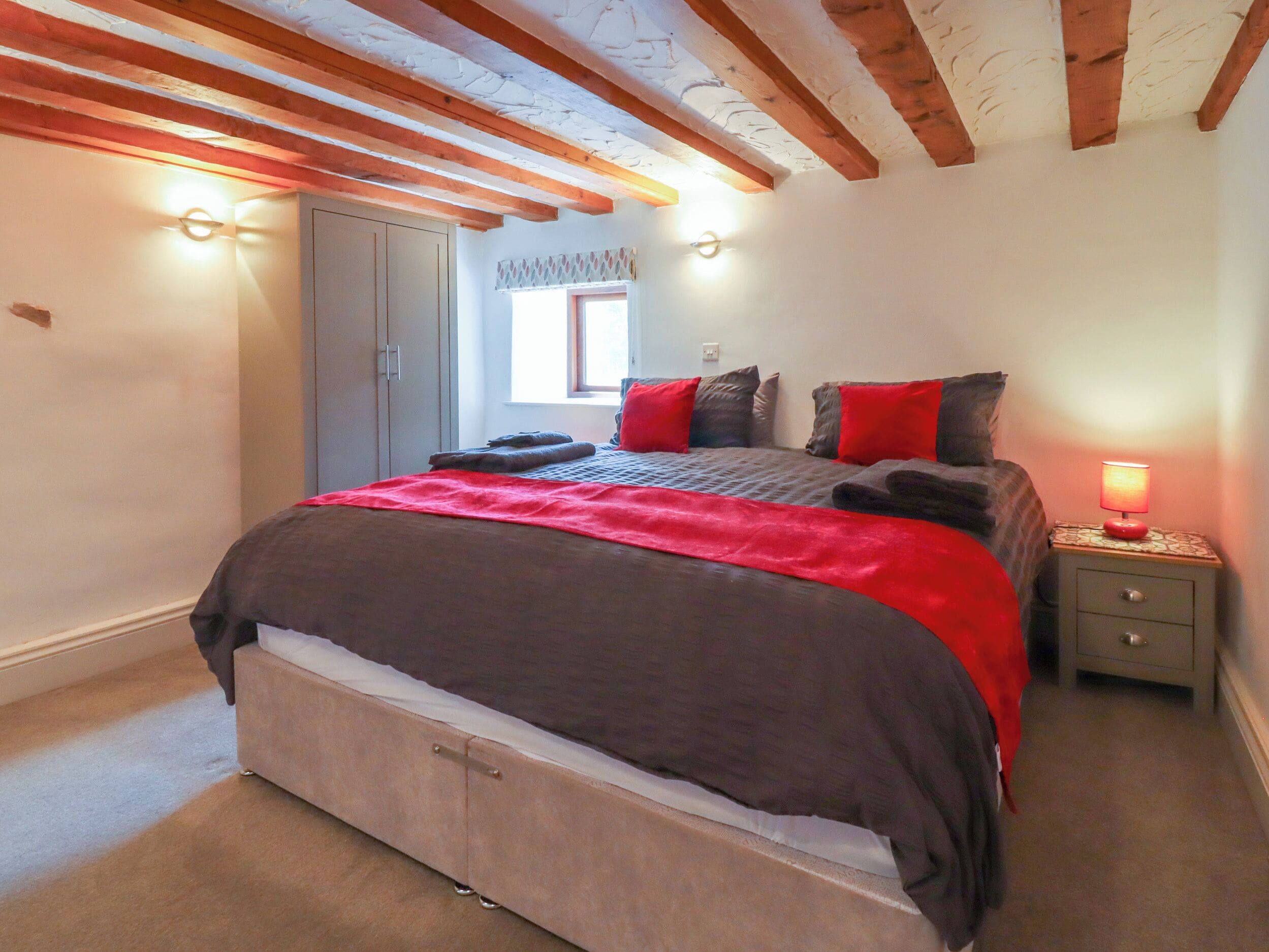 A bedroom with a bed, bedside table, and a window.