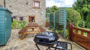 Ein Steinhaus mit einem Holztisch und einem tragbaren Grill im Vordergrund.