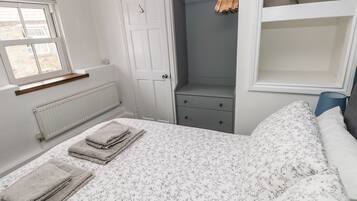 Un dormitorio con cama, armario, radiador y ventana.