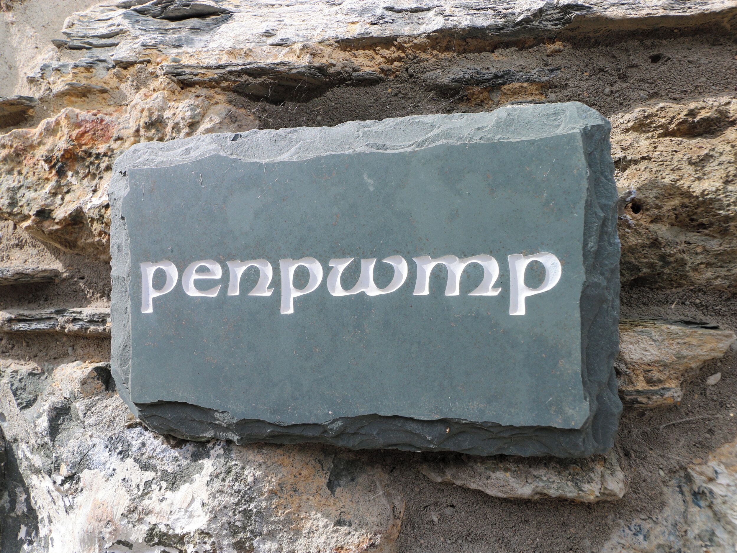 A stone sign with the inscription "penpump" on a rocky surface.