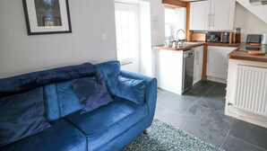 Un appartement moderne avec un canapé bleu, une cuisine dotée de meubles blancs et un tableau encadré accroché au mur.