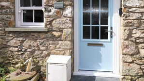 Un bâtiment en pierre avec une porte bleu clair et une fenêtre sur laquelle est apposée une enseigne.