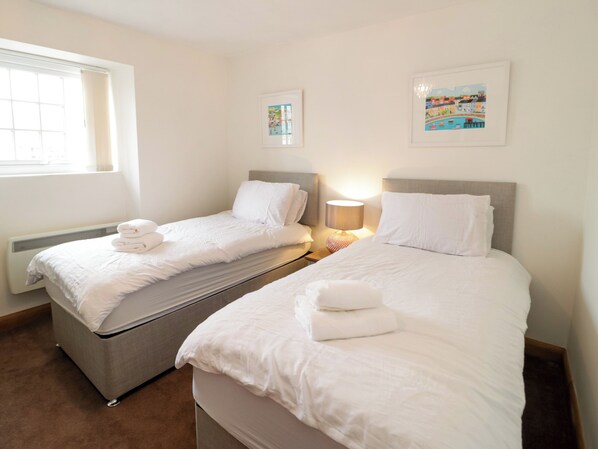 A hotel room with two beds, a window, a radiator, and two framed pictures on the wall. - 3 Moranedd (Moelfre)