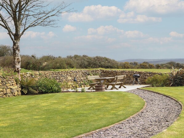 A stone wall, a picnic table, and a grassy area with a tree.