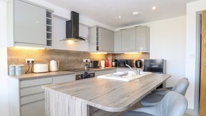 Une cuisine moderne dotée d’un îlot central, de meubles gris et d’appareils électroménagers en acier inoxydable.