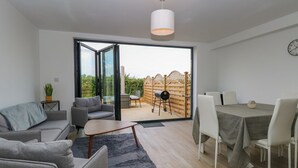 Un salon moderne avec un canapé gris, une table basse et un coin repas comprenant une table et des chaises.