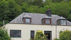 A two-story house with a sloped roof, dormer windows, and a chimney.