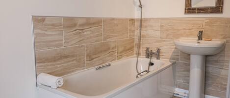 A modern bathroom with a freestanding bathtub, a wall-mounted mirror, and a pedestal sink.