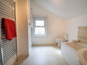 A bathroom with a white toilet, a bathtub, and a window. - Mackerel Cottage (Weymouth)