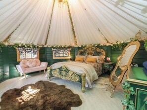 A tented room with a bed, a chair, a mirror, and a fur rug. - Applejacks Orchard (Holywell)