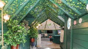 A cozy, green-themed interior with a vaulted ceiling, a sofa, a TV, and a patterned rug. - Applejacks Orchard (Holywell)