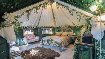 Un dormitorio con cama con dosel, una chaise longue, un espejo y un aparador.