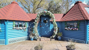 A blue wooden house with a red roof, a blue door, and potted plants. - Applejacks Orchard (Holywell)