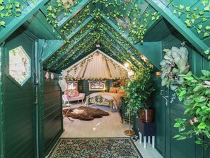 Ein gemütliches Schlafzimmer im Dachgeschoss mit schrägen Wänden, einem Bett, einem Sessel und einem großen Fenster.