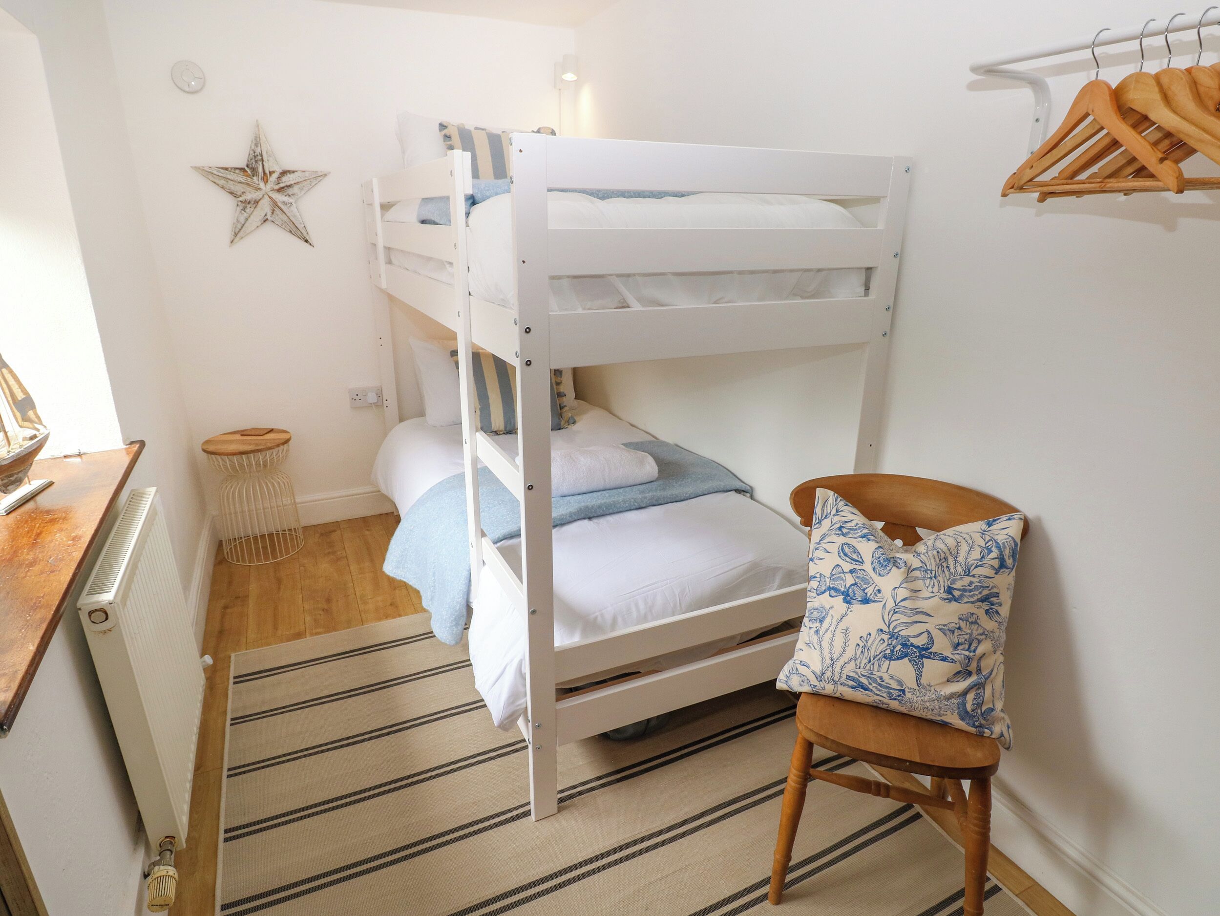 Habitación con literas, una silla de madera y una decoración de estrellas en la pared.