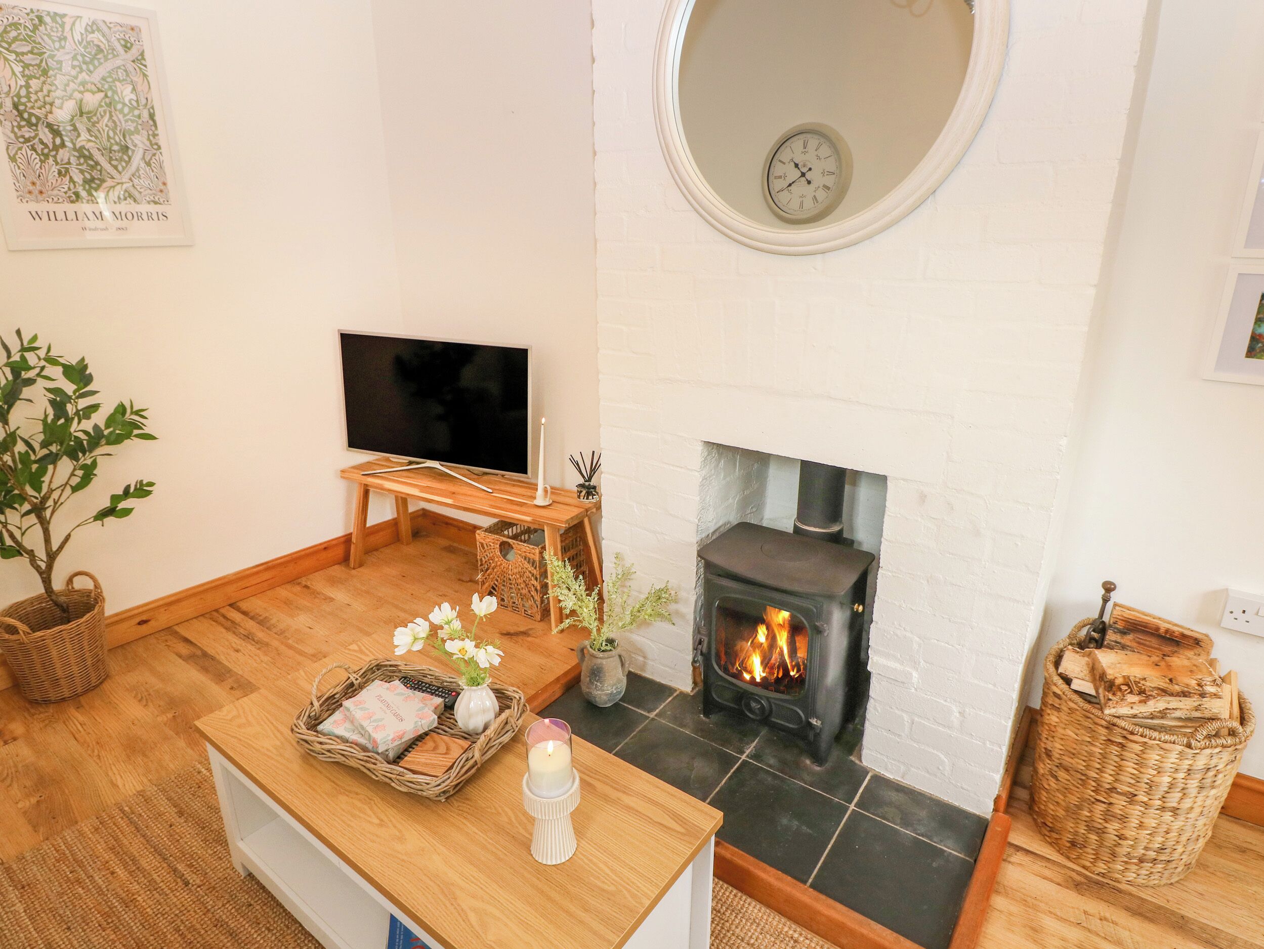 A cozy living room with a fireplace, a television, and a clock on the wall.