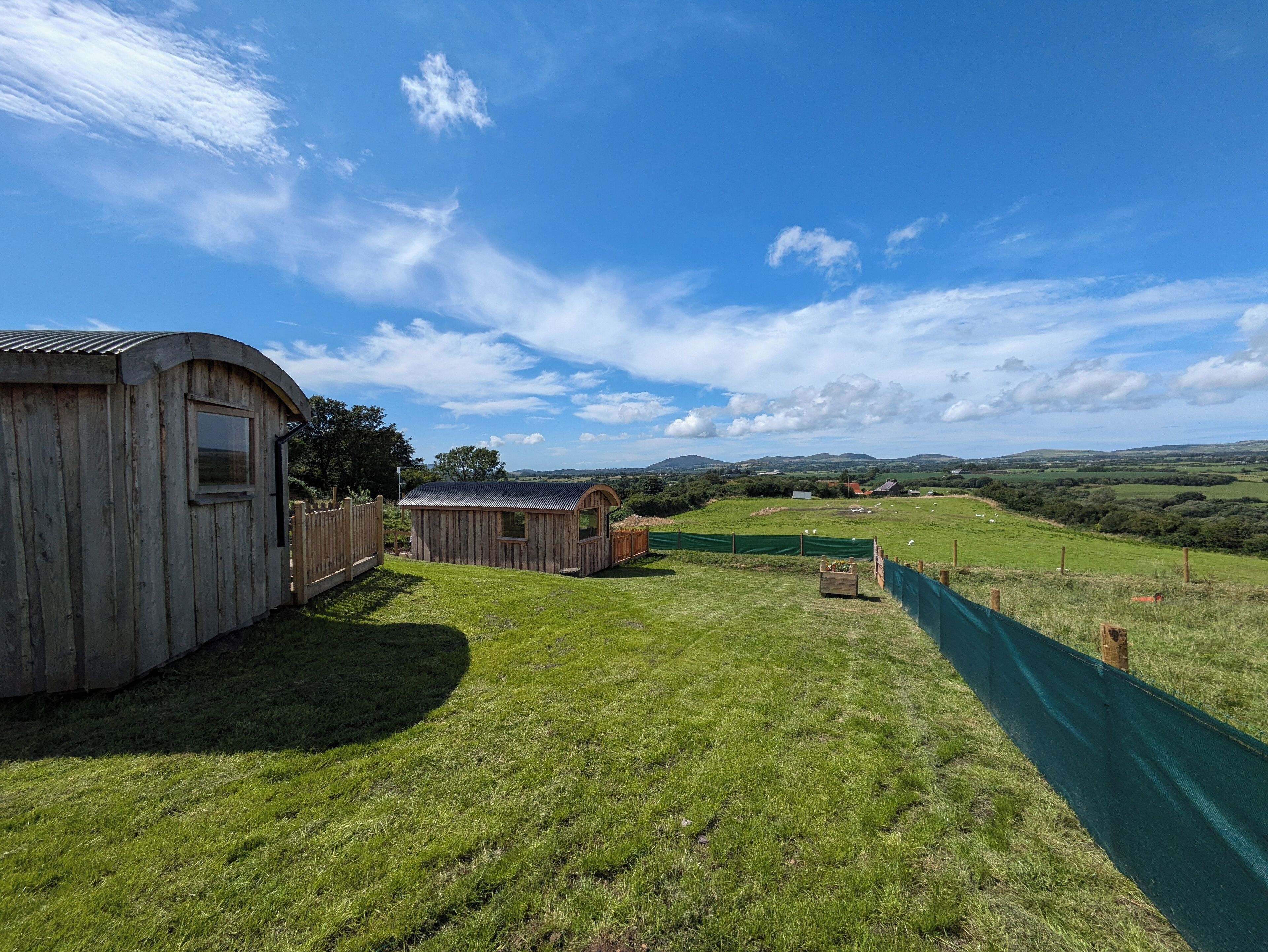 A rural property with a wooden barn, a smaller wooden structure, and a fenced field.