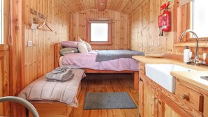 A cabin with two beds, a small kitchenette, and a window. - Hafan Gelli Sheperds Hut - Enlli (Pwllheli)