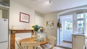 A kitchen with a dining table, chairs, a microwave, and a refrigerator. - Pendennis (Sherborne)