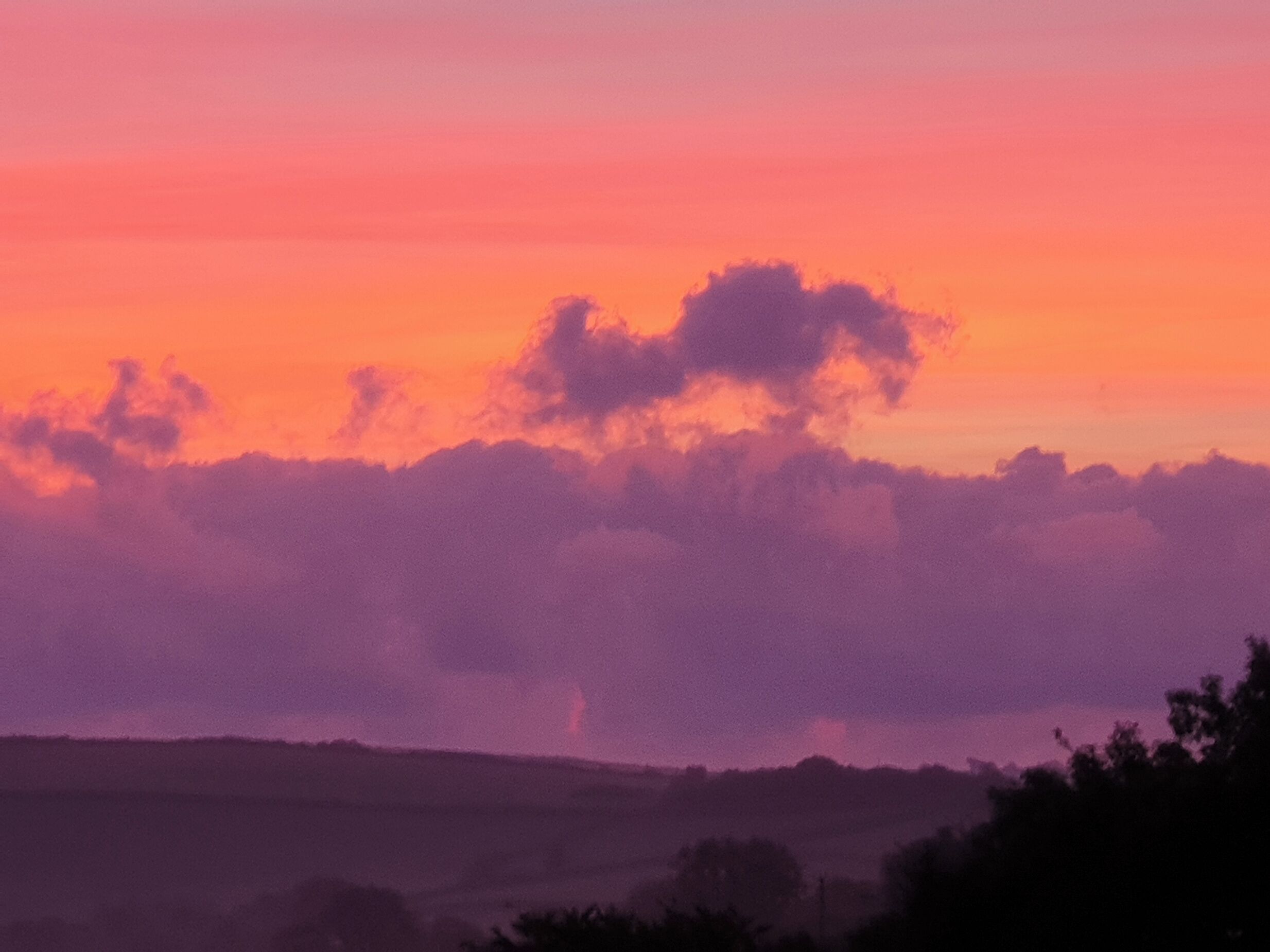 Un atardecer sobre un paisaje montañoso con una formación nubosa destacada.
