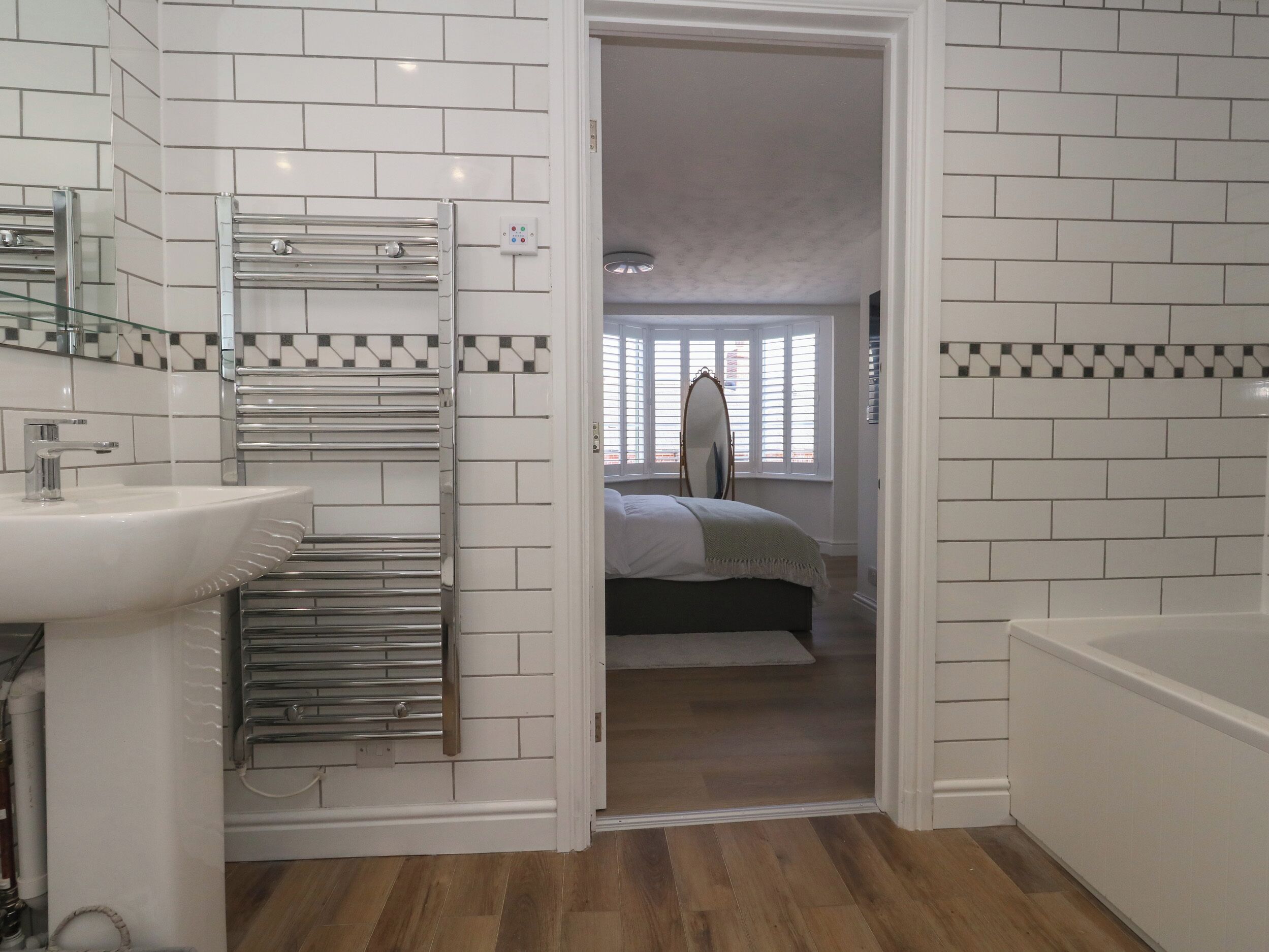 A bathroom with a white sink, a glass shower enclosure, and a towel rack.
