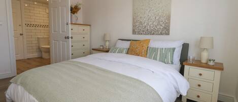 A bedroom with a bed, nightstands, a dresser, and a door leading to a bathroom.