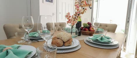 A dining table set with plates, glasses, and a bowl of fruit.