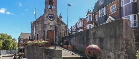 A historic building with a clock tower, a stone wall, and a metal railing.