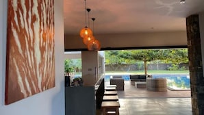 Un interior moderno con vista a la piscina, bancos de madera y lámparas colgantes.