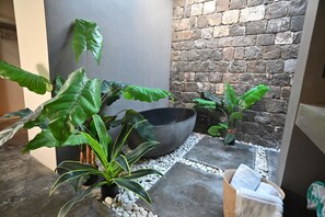 A stone-tiled patio with a large black bowl, potted plants, and a woven basket with towels. - Elite 600M/square Villa with garden in Grand Bay (Grand Baie)