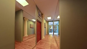 A hallway with a polished wooden floor, green walls, and a red door. - HOTEL ALEF (Kraków)