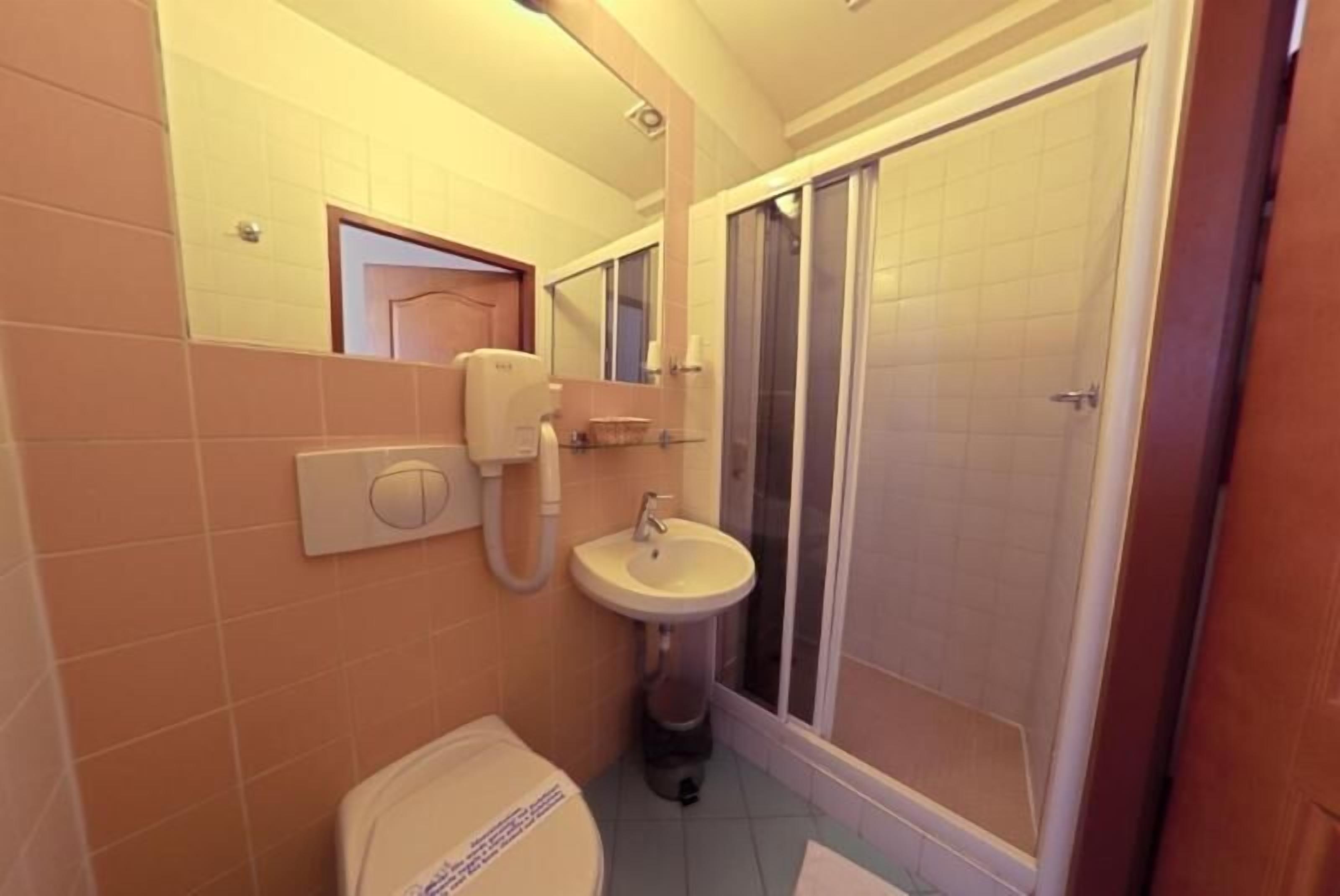 A bathroom with a toilet, sink, and shower.