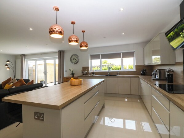 A modern kitchen with a central island, pendant lights, and a large window providing natural light.