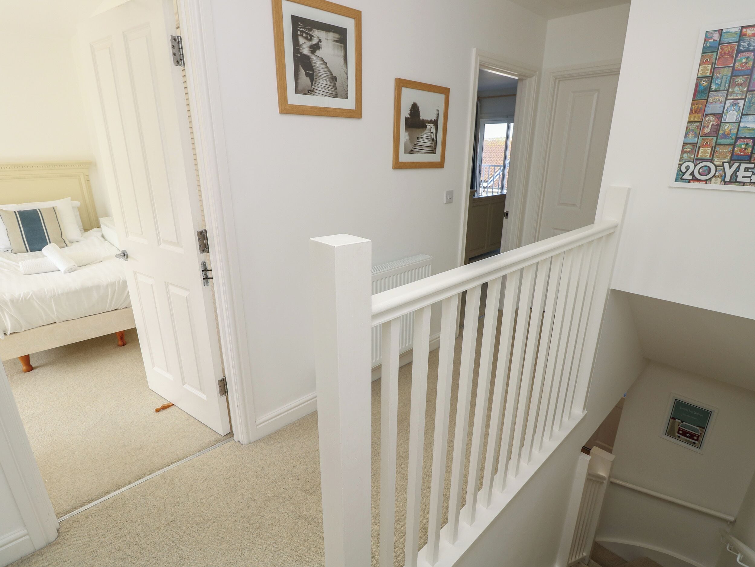 A bedroom with a bed, a door leading to another room, and a staircase with a white railing.