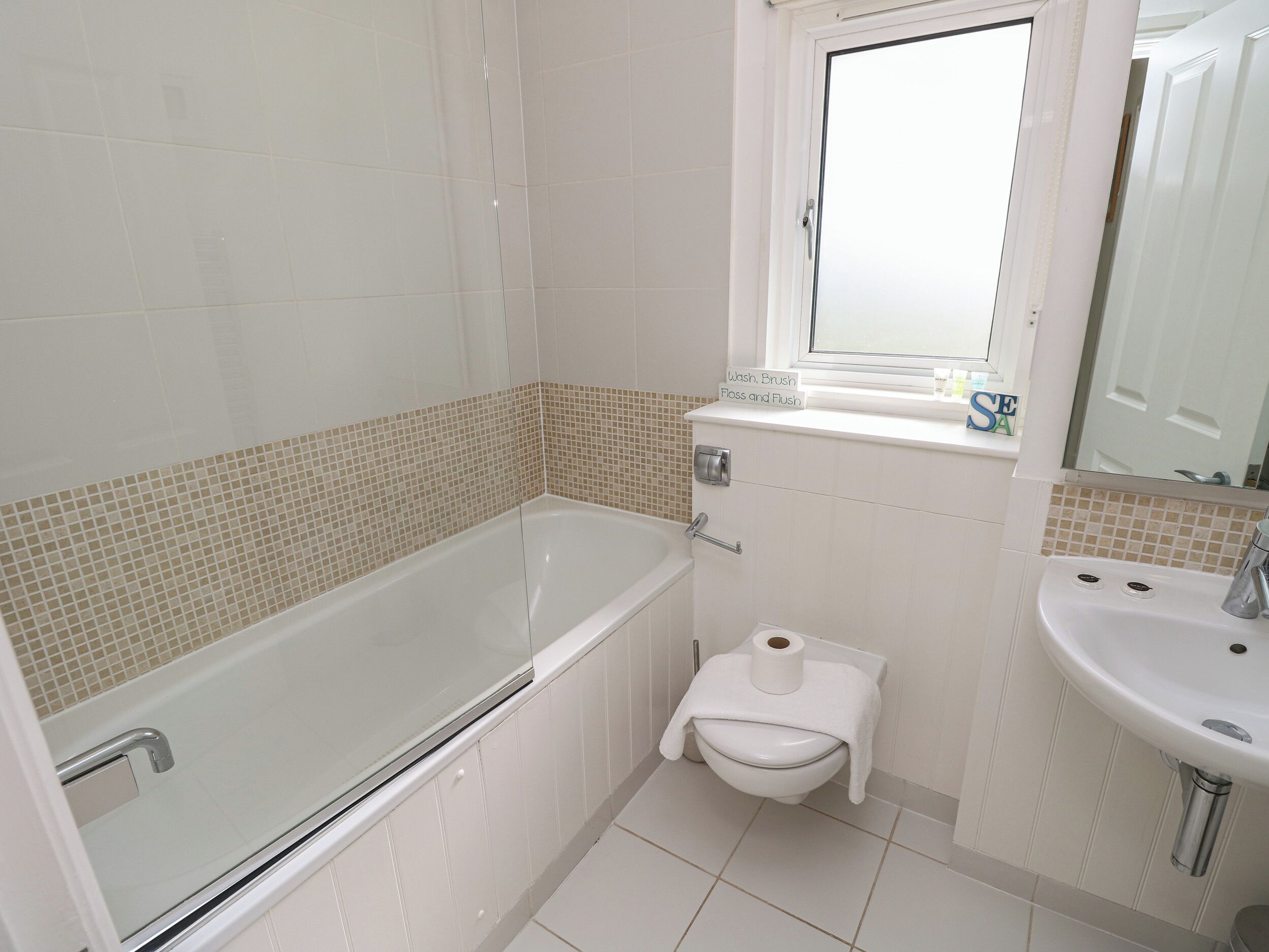 Een badkamer met een bad, toilet, wastafel en een raam.
