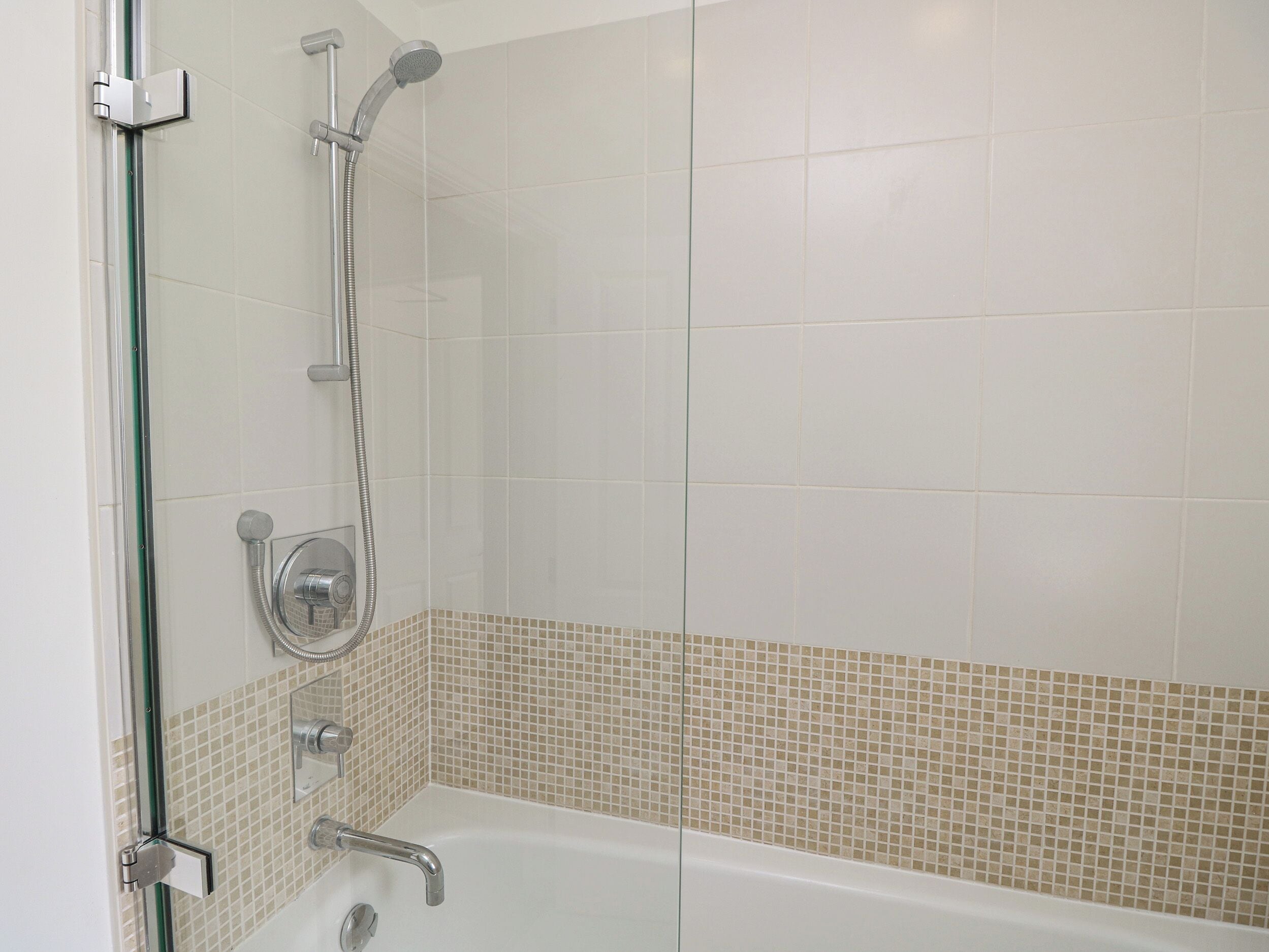 Une salle de bain moderne avec une douche à parois de verre, une baignoire et un sol carrelé.