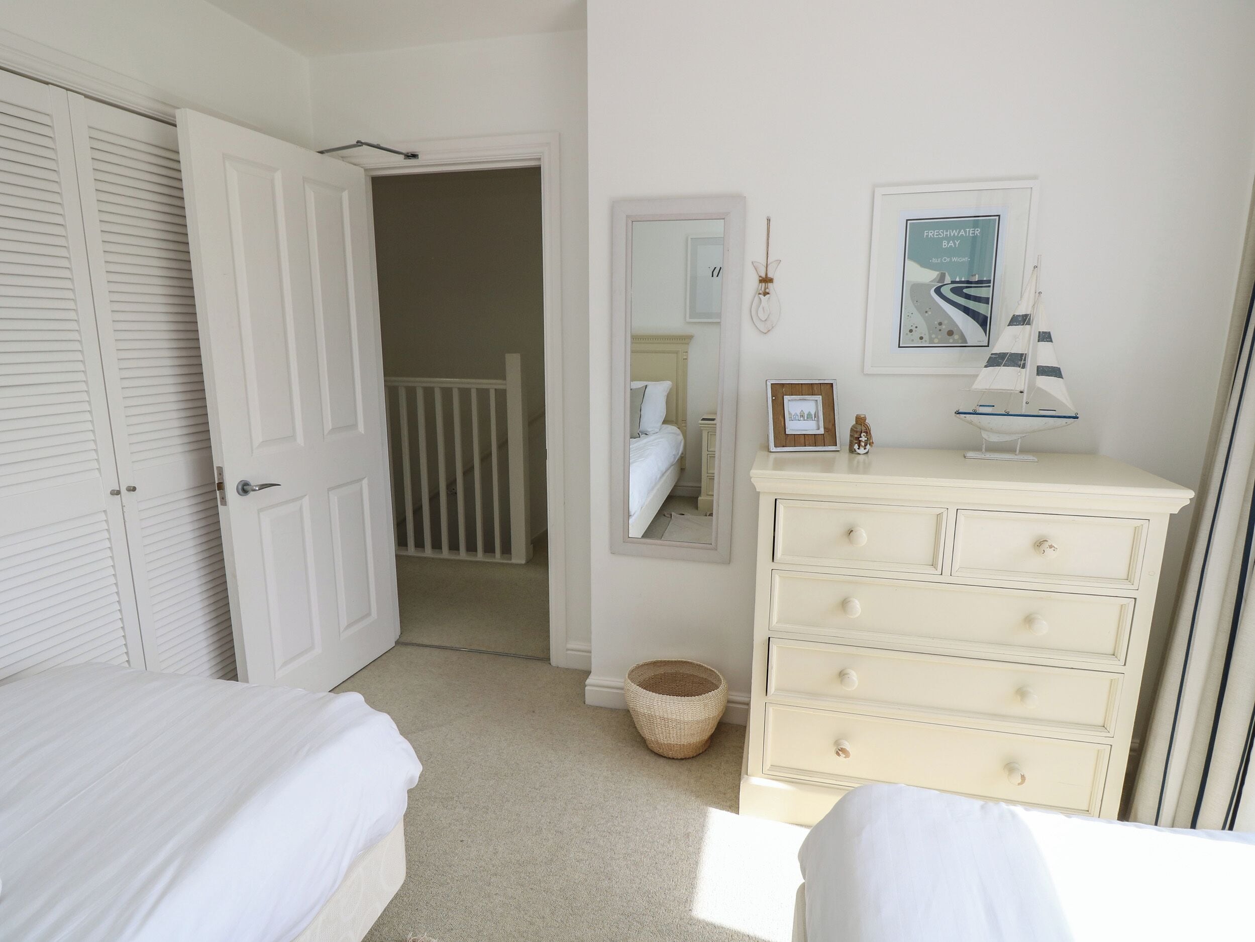A bedroom with a bed, a dresser, a mirror, and a door leading to a staircase.