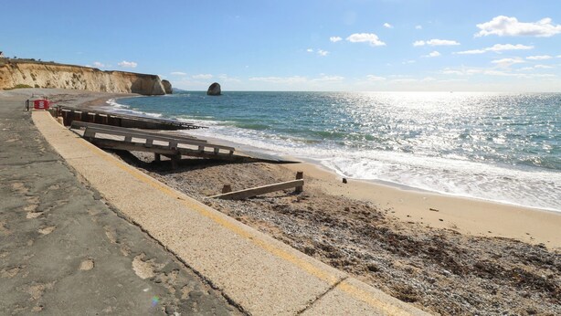 A coastal walkway with a rocky cliff, a wooden bridge, and a sandy beach. - Whitfield P5 (Yarmouth)