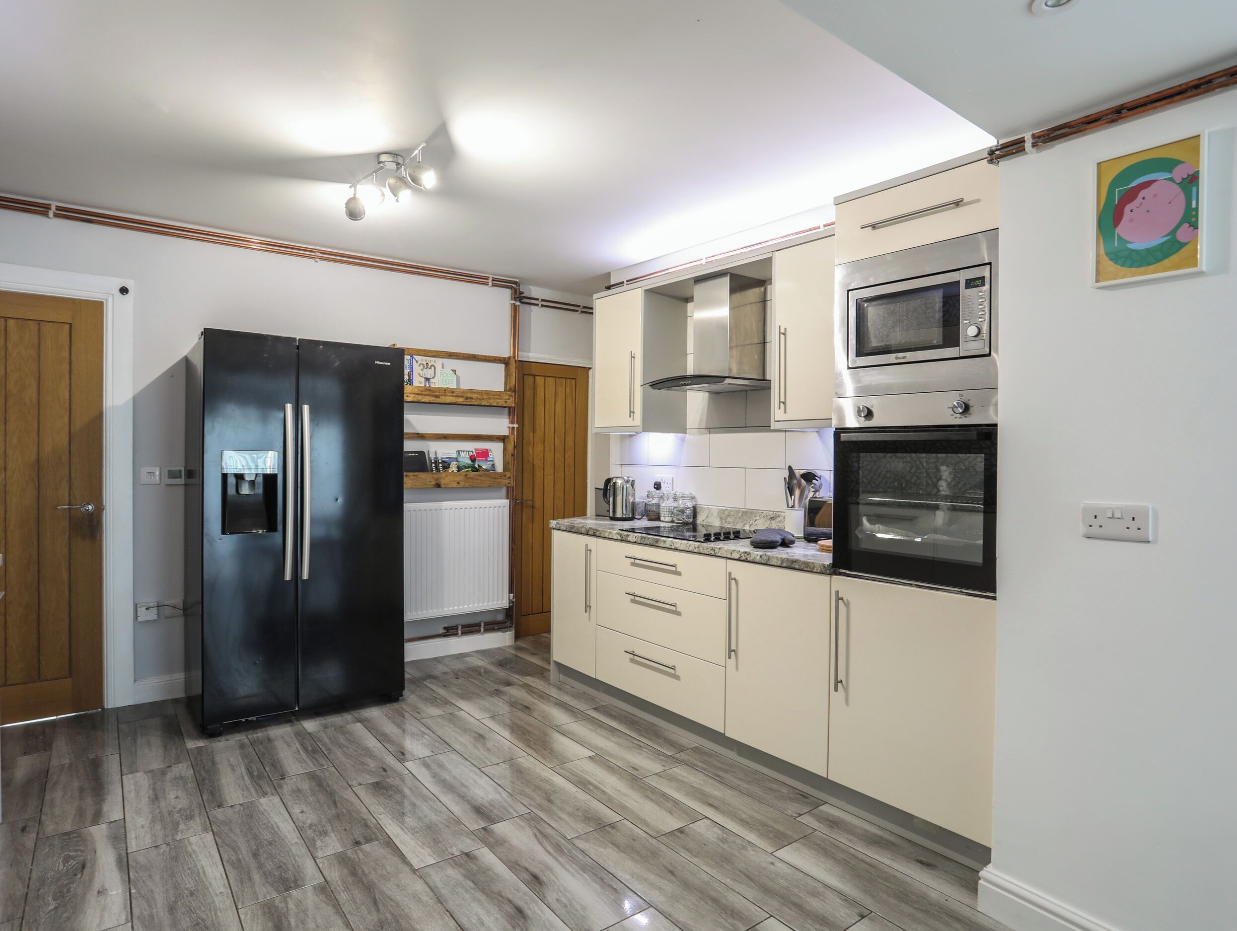 A modern kitchen with a black refrigerator, stainless steel oven, and microwave.