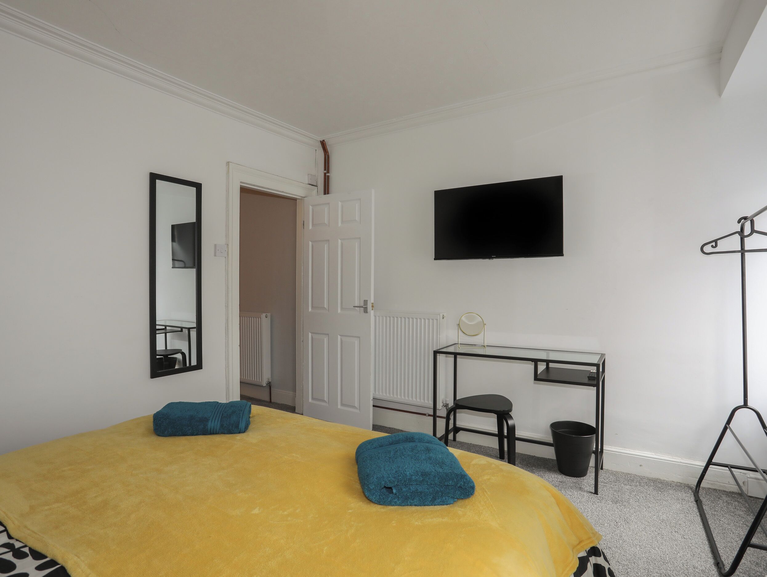 Hotelkamer met een bed, bureau, stoel, televisie en kapstok.