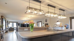 Een moderne keuken met een centraal eiland, hanglampen en een groot raam.